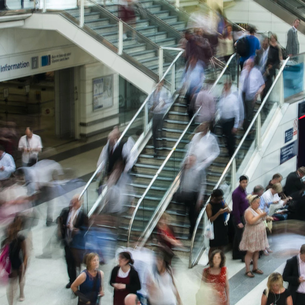 An image of people walking down stairs in a busy train station.