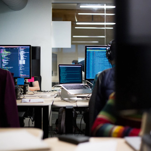 Photograph of an open plan office with several people working on computers.